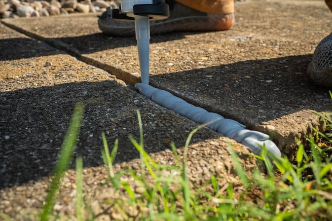 Applying caulk to an expansion joint in sidewalk