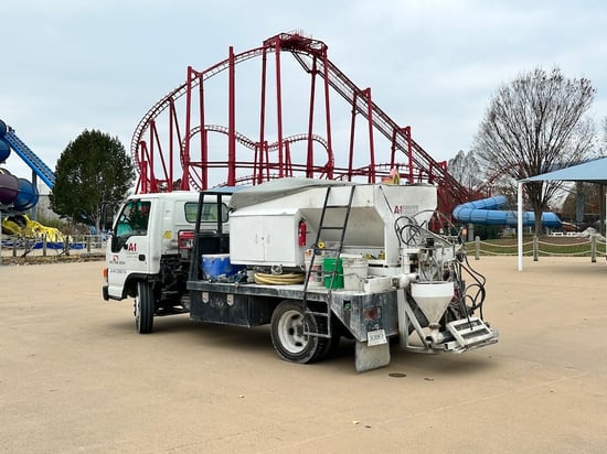 Concrete leveling pump truck and equipment in front of roller coaster at amusement park