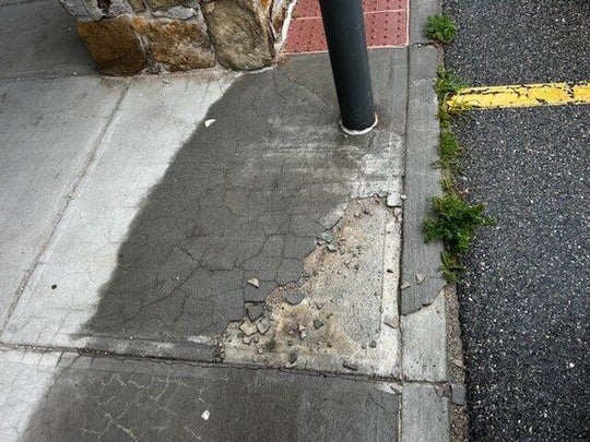Concrete overlay crumbling off the surface of a sidewalk slab
