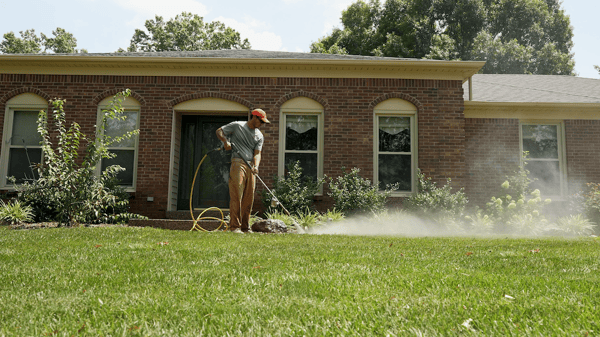 Man spraying concrete walkway with pressure washer