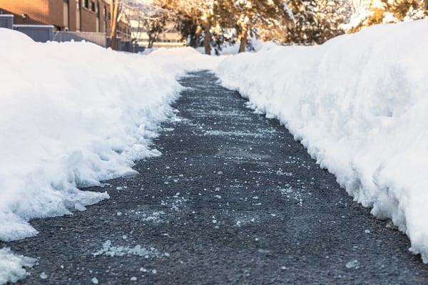 Salt on concrete path in winter with snow banks on either side