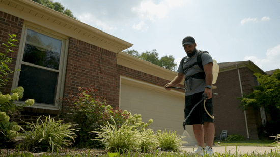 Man spraying concrete sealer onto walkway