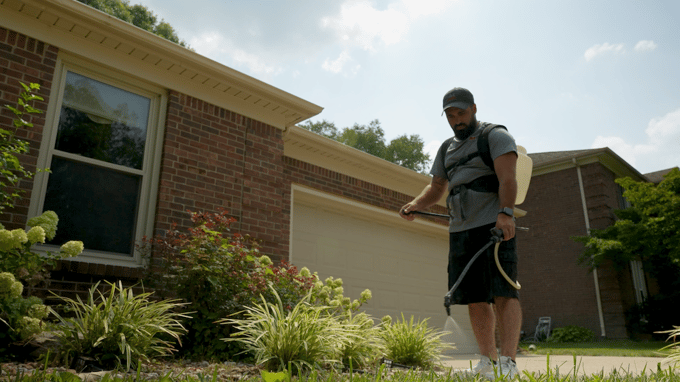 Man spraying concrete sealer onto walkway