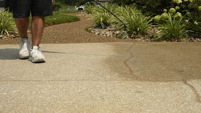 Closeup of penetrating concrete sealer being sprayed onto concrete driveway