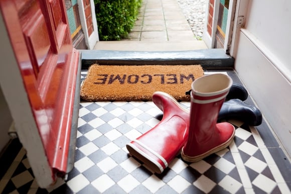 Entryway in home with welcome mat and rubber boots