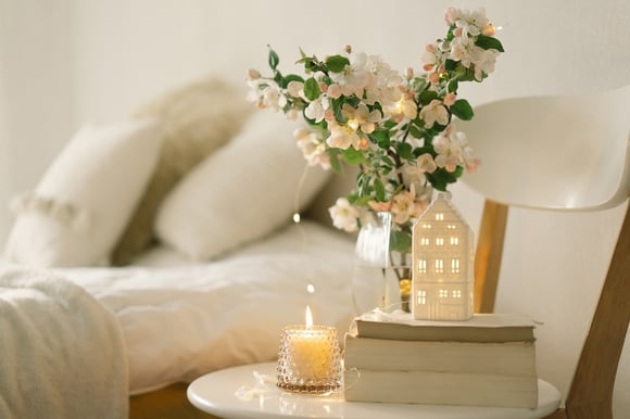 Flowers and candle sitting on chair as side table next to bed