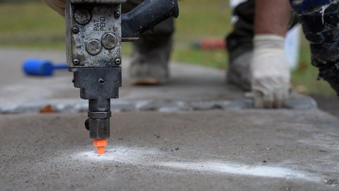 Foam concrete leveling process being performed on sunken concrete slab