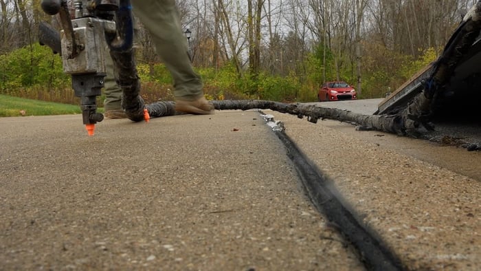 Technician injecting expanding ployurethane foam below concrete slab