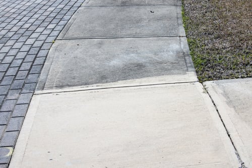 Concrete sidewalk with half clean and half dirty after pressure washing