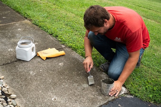 Man patching hole in concrete after lifting the slab with concrete leveling