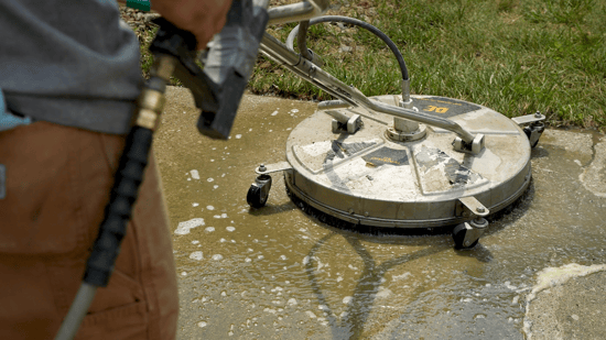 High-powered professional pressure washer cleaning dirty concrete driveway