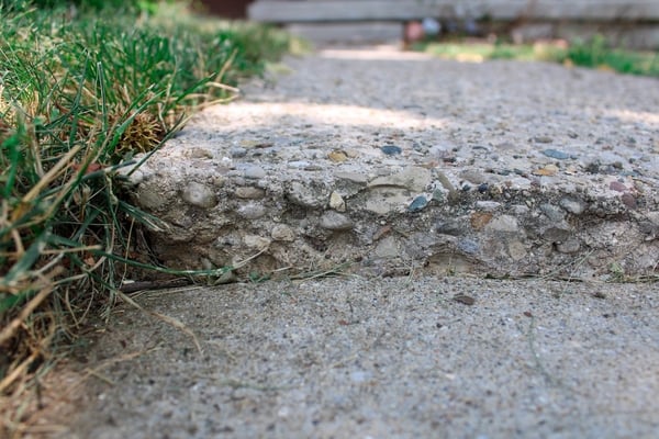 Trip hazard close-up of aggregate concrete sidewalk slab that has settled