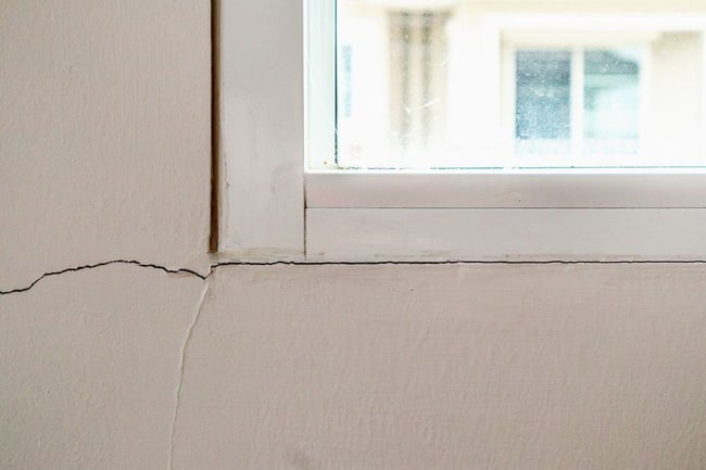 Gap in window frame and crack in wall