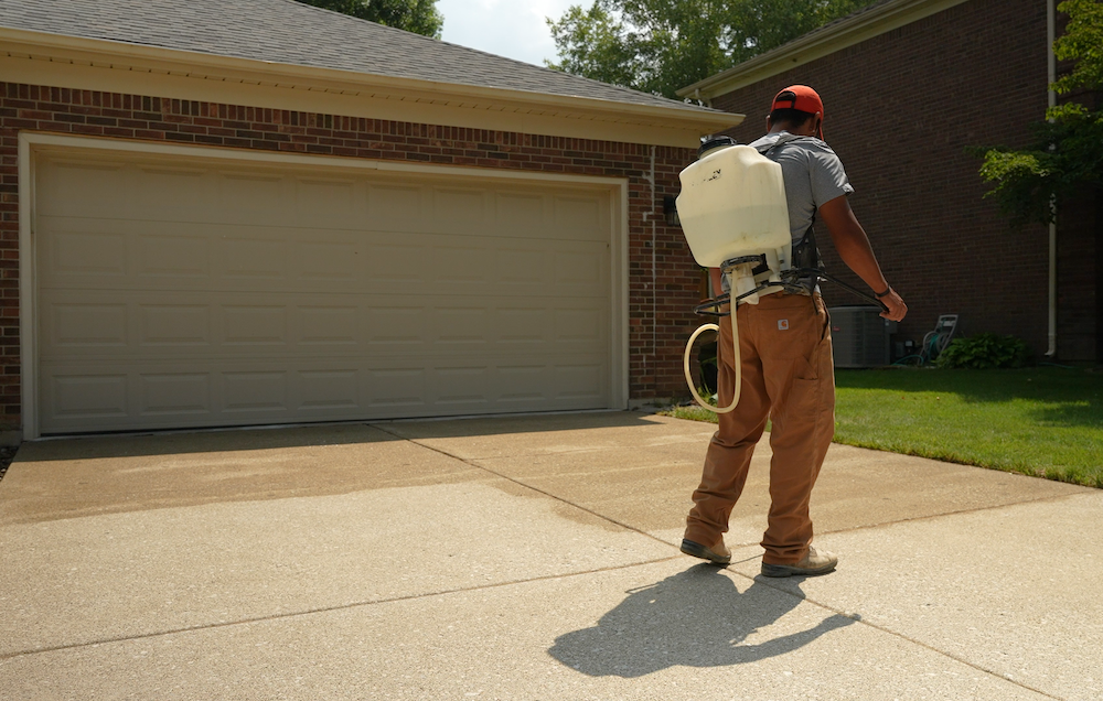 Man spraying penetrating concrete sealer on driveway