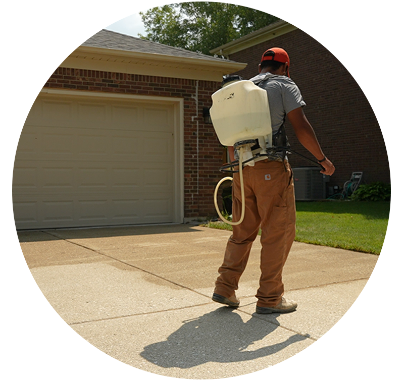 Man spraying penetrating concrete sealer on concrete driveway