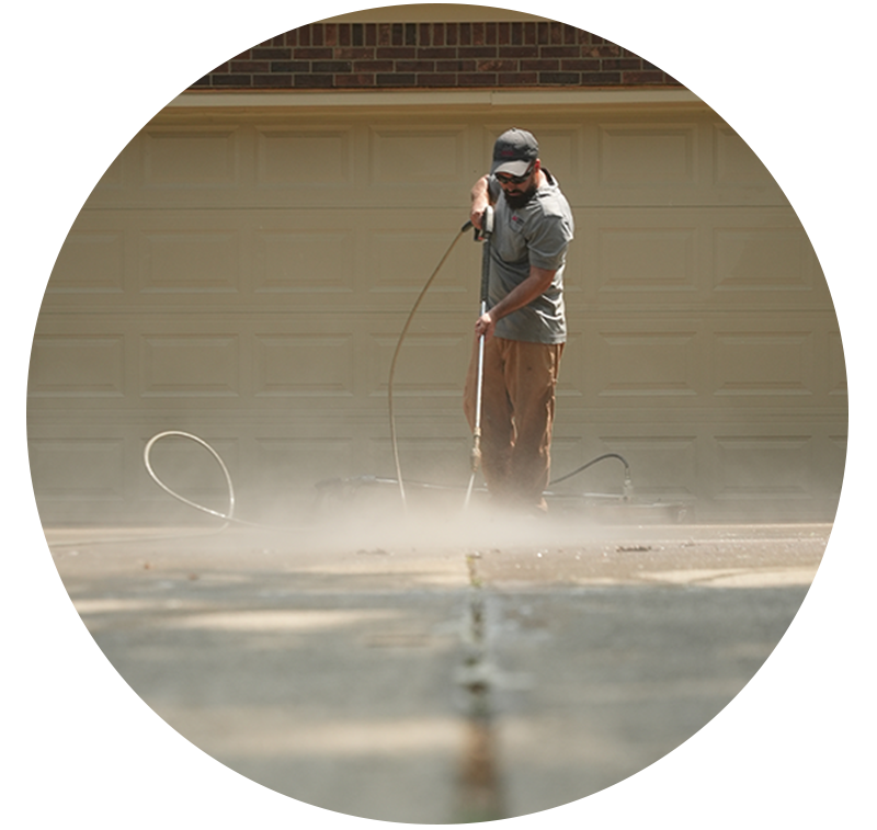 Man cleaning concrete driveway with wand attachment