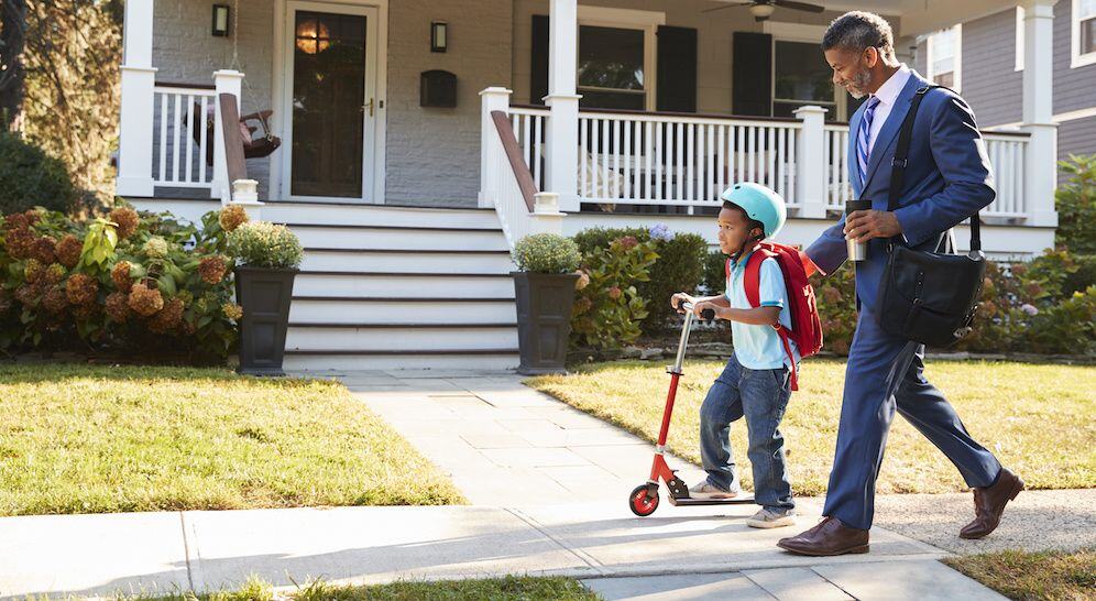 Man and son walking on concrete sidewalk